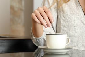 A cup of coffee being stirred with a spoon.