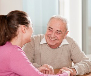 A woman sitting talking to an elderly man.