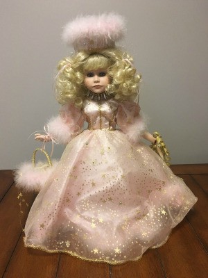 Value of a Porcelain Doll - doll wearing a fancy light pink dress with hat and curly blonde hair