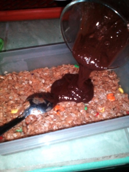 pouring melted chocolate on peanut butter mixture in square pan
