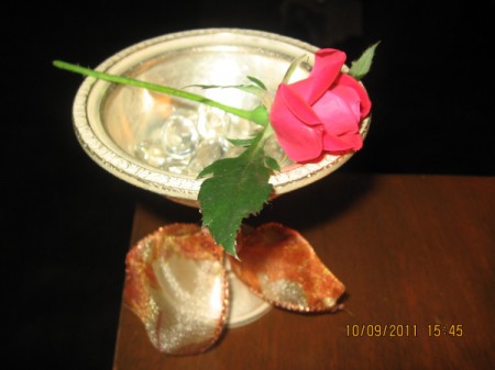 An antique silver dessert cup holding a red rose.