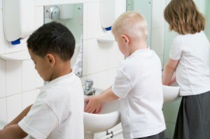 Children washing their hands in a school bathroom.