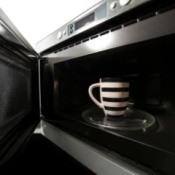 An open microwave oven, with a mug inside.