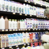 A woman shopping in the milk aisle at a grocery store.