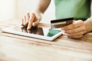 A man using a tablet to pay bills with a credit card.