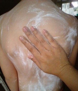 A hand applying cornstarch to a boy's back.