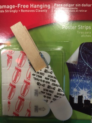 A clothespin with a Command removable sticker on it.