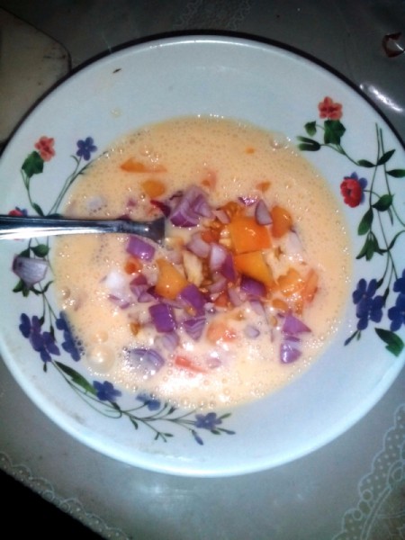 adding chopped onion and tomato to eggs