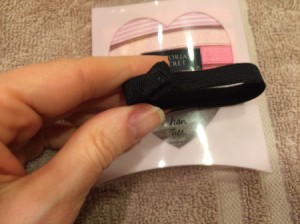 A hair tie being held in front of the packaging.