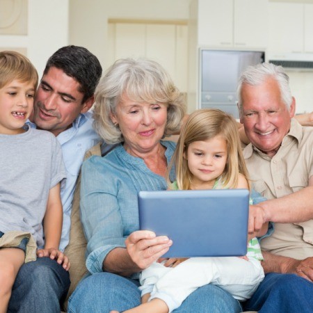 A family using a laptop computer on the couch.