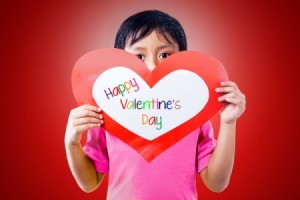 A boy holding a heart shaped Valentine card.