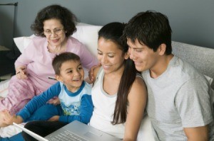 A family using a laptop computer on a couch.