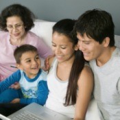 A family using a laptop computer on a couch.