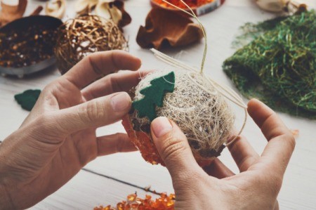 Hands assembling a round Christmas ornament.
