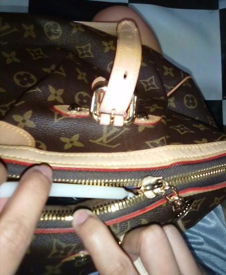 A candle being used to lubricate the zipper of a purse.