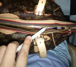 A candle being used to lubricate the zipper of a purse.