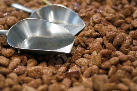 A pile of cinnamon toasted almonds with a scoop.