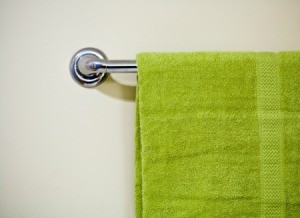 A towel rack with a green towel hanging on it.