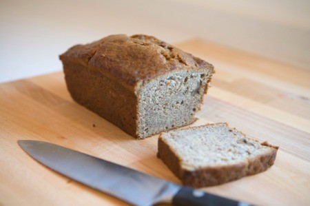 A loaf of banana bread with a slice cut out of it.