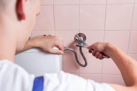 A plumber repairing a leaking toilet.