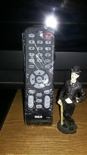 A television remote control covered in plastic wrap.