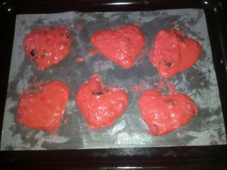 heart shaped red cookies on baking pan