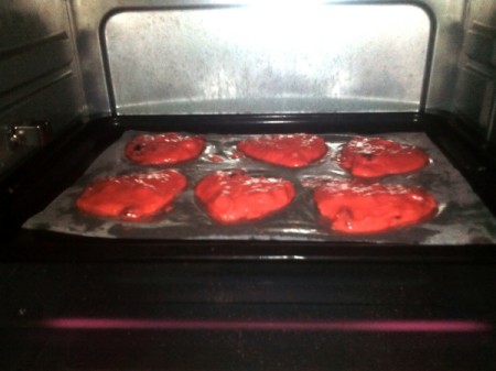 heart shaped red cookies on baking pan