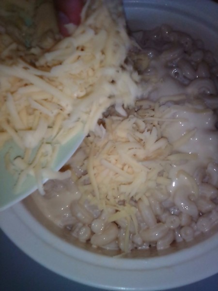 adding cheese to creamy macaroni