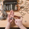 A person assembling jewelry on a craft table.