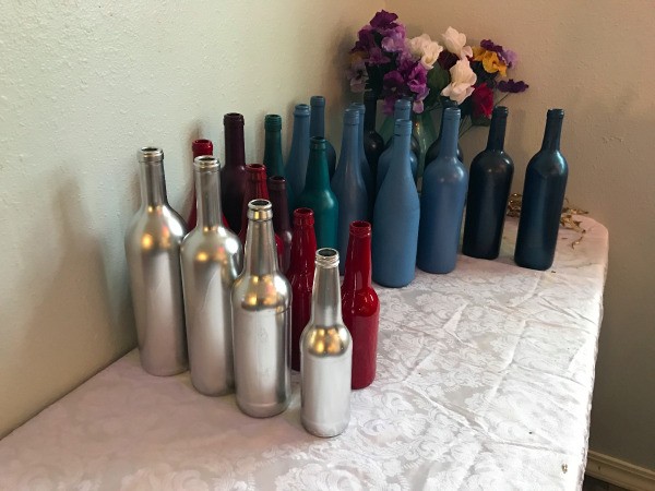 Rows of different colored painted wine bottles.