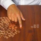 A hand counting pennies on a wooden desk.