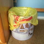 A popcorn tin being used as a trash can.