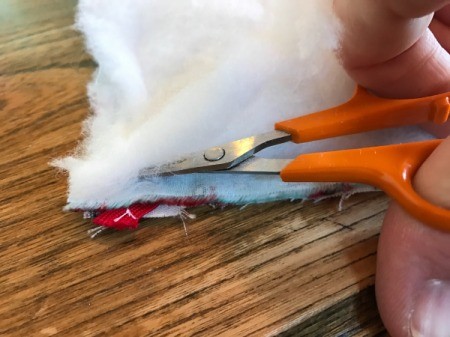 Whole Cloth Tied Quilt with Ric Rac Trim - closeup of removing excess batting after sewing seam