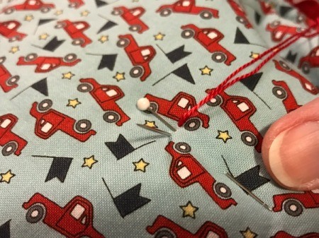 Whole Cloth Tied Quilt with Ric Rac Trim - using perle floss to complete a running stitch coming up and going down next to pins