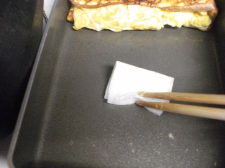 oiling pan with omelet at one end