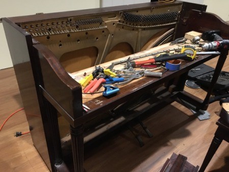 An upright piano being used as a desk.
