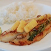 Pan Fried Tilapia with green onion and ginger chunks on plate