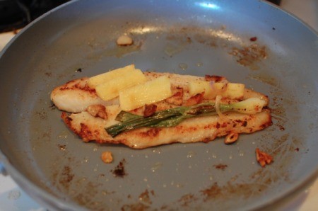 Pan Fried Tilapia with green onion and ginger chunks in pan