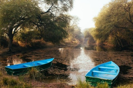 A lake at sunset with two blue boats.