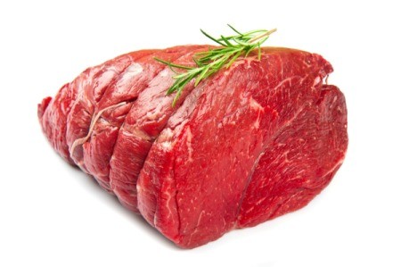 An uncooked beef roast with a sprig of rosemary on top.