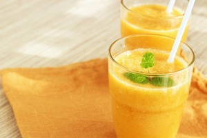 Two orange colored smoothies in glasses.