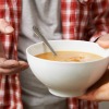 A bowl of soup being handed to a hungry person.