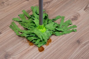 A spill on a laminate floor, being cleaned up with a mop.