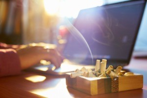 An ashtray on a computer desk in an apartment.