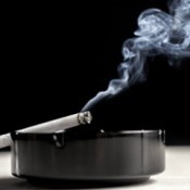 Smoke rising from a cigarette in an ashtray.