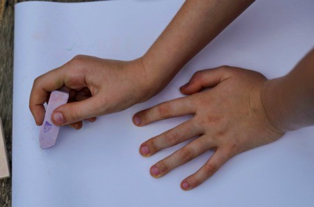 A child drawing a picture on paper with chalk.