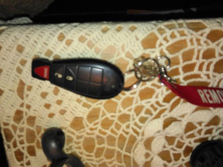 A car key and remote on a bedside table.