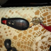 A car key and remote on a bedside table.