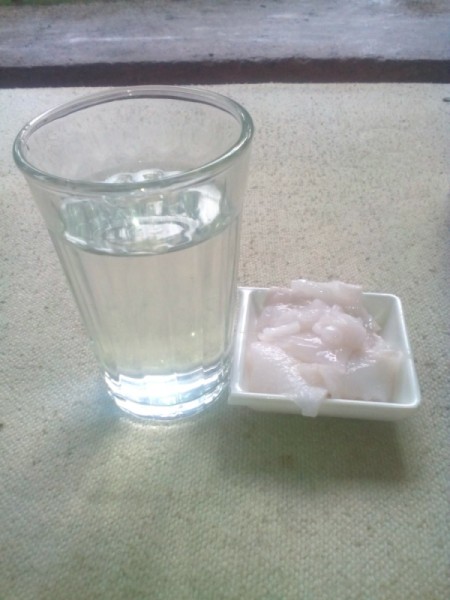 A dish of fresh coconut and a glass of water.