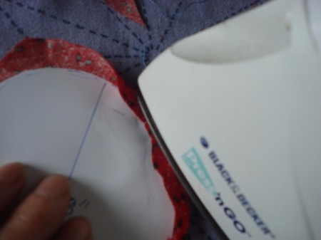 Pot Holders from Shoulder Pads - On these half-sized fabric pieces, use an iron and the pattern to fold edges as it will be easier to sew.